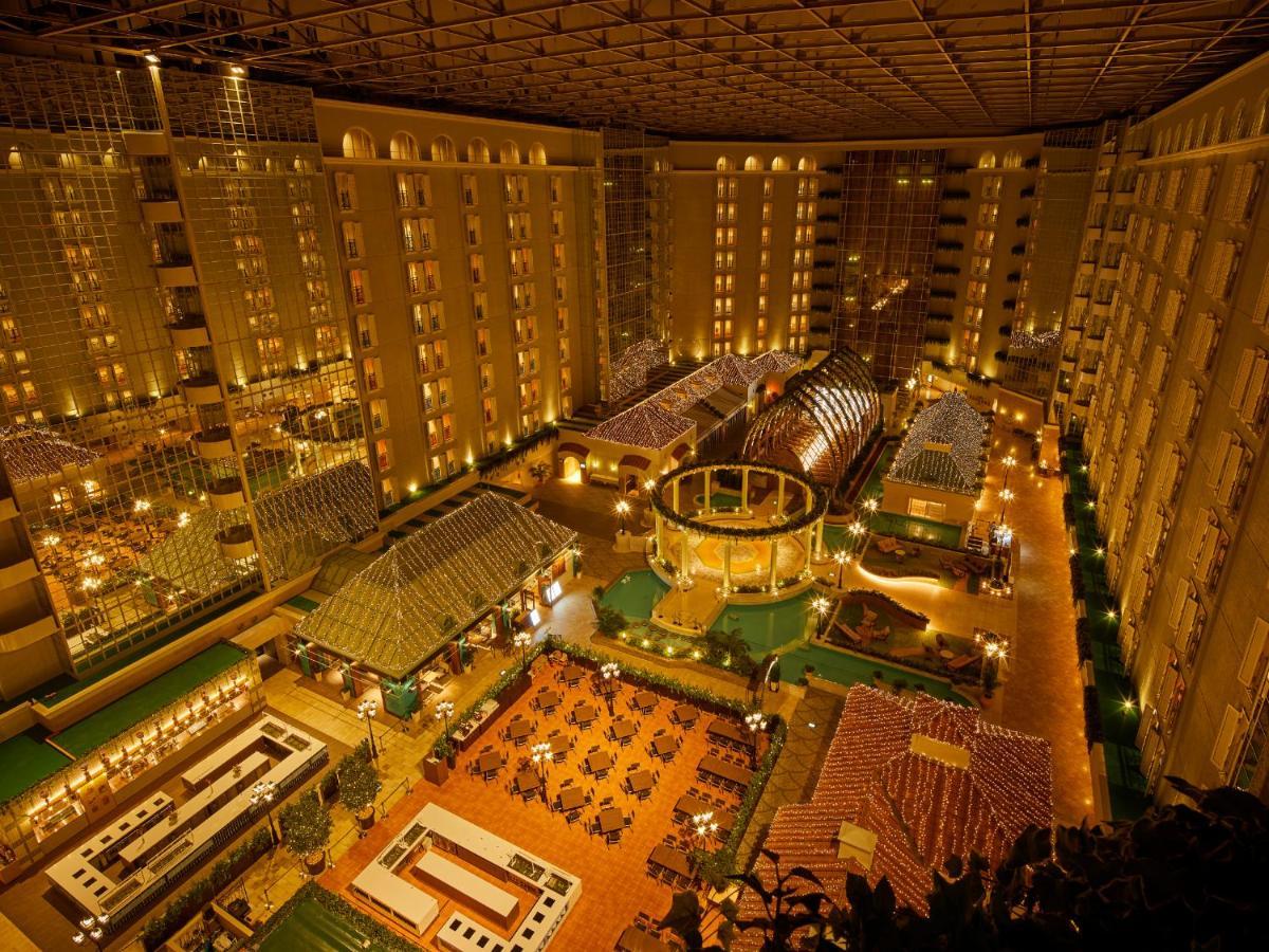 Grand Nikko Tokyo Bay Maihama Hotel Urajaszu Kültér fotó The photo shows a large, illuminated atrium of a hotel or resort complex. Several floors of what appear to be guest rooms or apartments surround the central area. The atrium contains a variety of amenities, including a pool or water feature, landscap