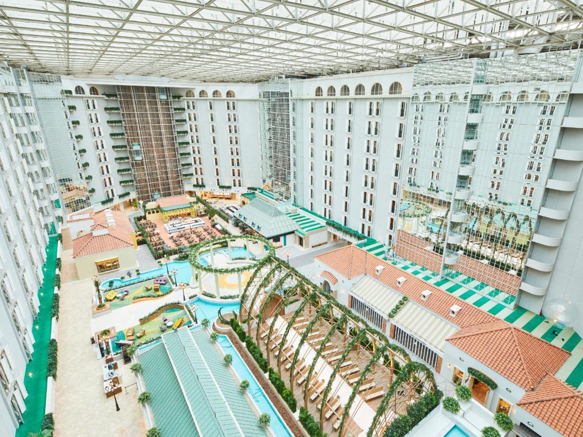 Grand Nikko Tokyo Bay Maihama Hotel Urajaszu Kültér fotó The photo shows a large indoor space, likely a hotel or resort atrium. The area features multiple levels of buildings surrounding a central courtyard. This courtyard includes various amenities such as pools, landscaped gardens, and recreational areas