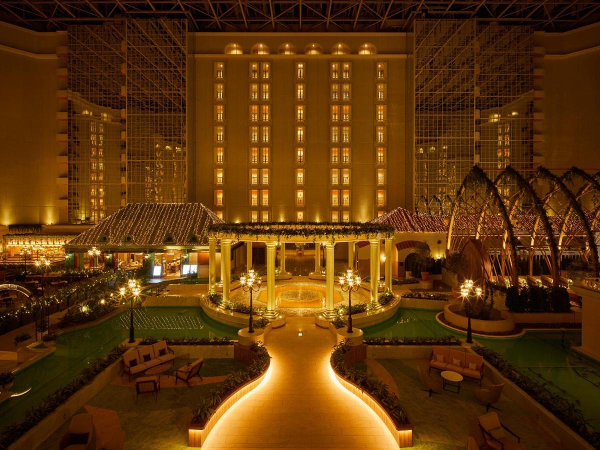 Grand Nikko Tokyo Bay Maihama Hotel Urajaszu Kültér fotó The photo shows a beautifully illuminated indoor space resembling a luxury hotel or resort. There are elegant architectural features, including large columns, arches, and decorative lighting. The area is designed with lush greenery and well-maintaine