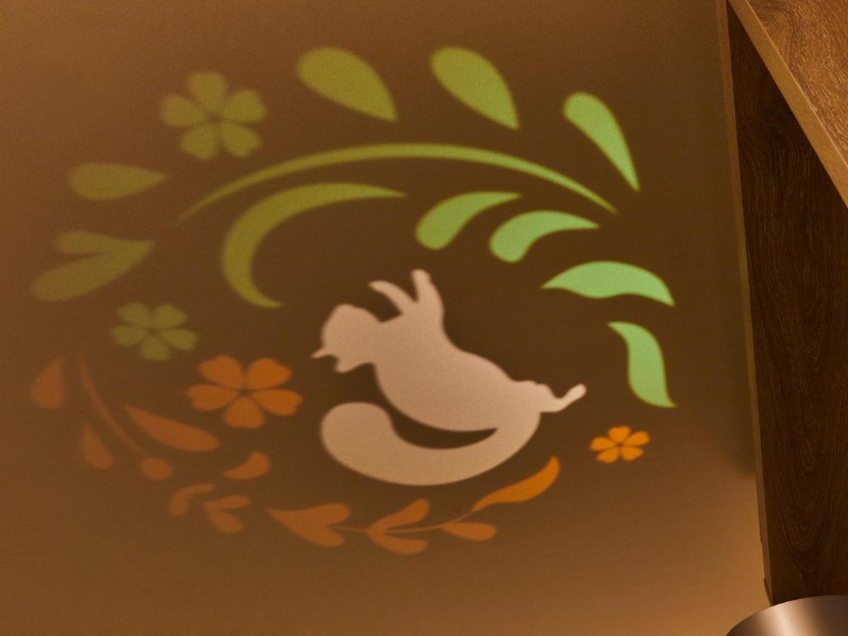 Grand Nikko Tokyo Bay Maihama Hotel Urajaszu Kültér fotó The photo shows a colorful projection on a surface that includes a playful illustration. The design features a white silhouette of a squirrel in a lively pose, surrounded by decorative elements like green leaves and flowers in shades of orange and ye