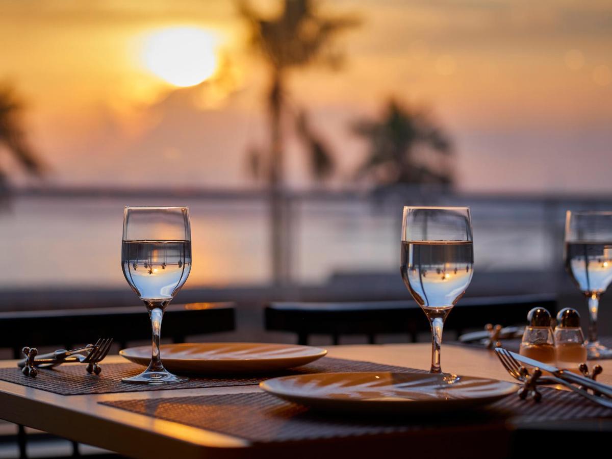 Grand Nikko Tokyo Bay Maihama Hotel Urajaszu Kültér fotó The photo depicts a picturesque dining setting at sunset. In the foreground, there are two elegantly arranged tables, each set with plates and glasses filled with water. The glasses are crystal clear, reflecting the warm colors of the sunset. Behind 