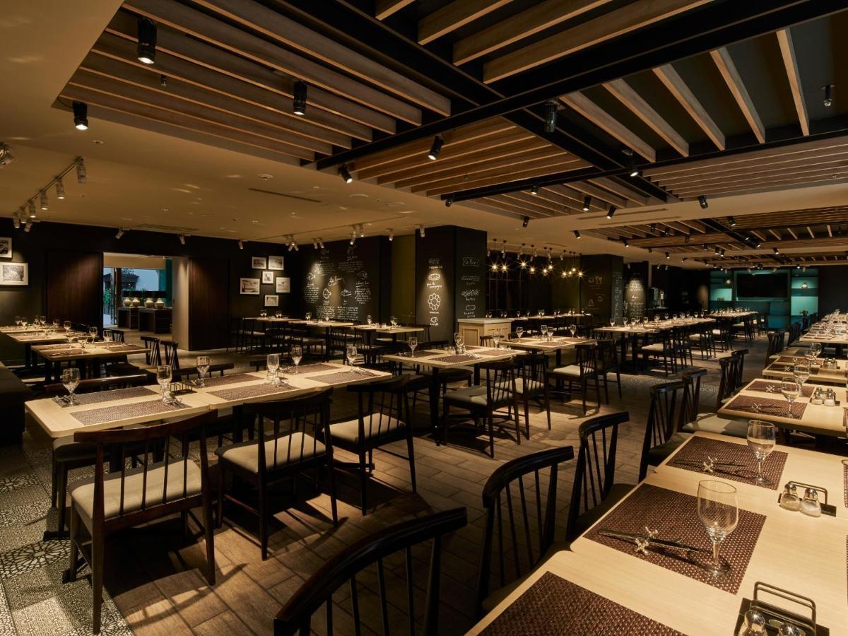 Grand Nikko Tokyo Bay Maihama Hotel Urajaszu Kültér fotó The photo shows the interior of a modern restaurant. The space features a spacious dining area with several long tables arranged in rows. Each table is set with dining utensils, plates, and glasses, indicating readiness for patrons. The lighting is s
