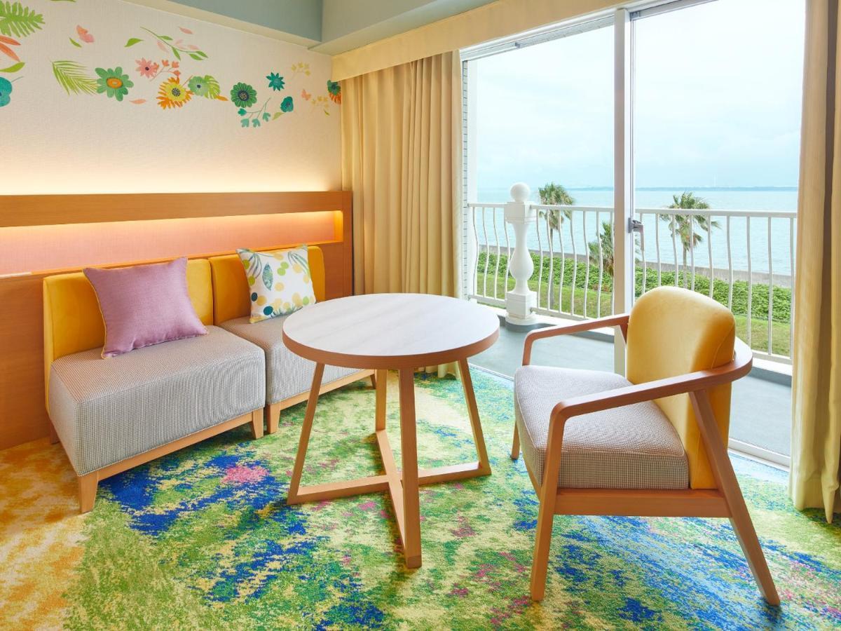 Grand Nikko Tokyo Bay Maihama Hotel Urajaszu Kültér fotó The photo shows a cozy interior space, likely a hotel room or a lounge area. It features a small round table in the center surrounded by comfortable seating. There are two chairs: one is a light wooden frame with a yellow seat, and the other has a mo