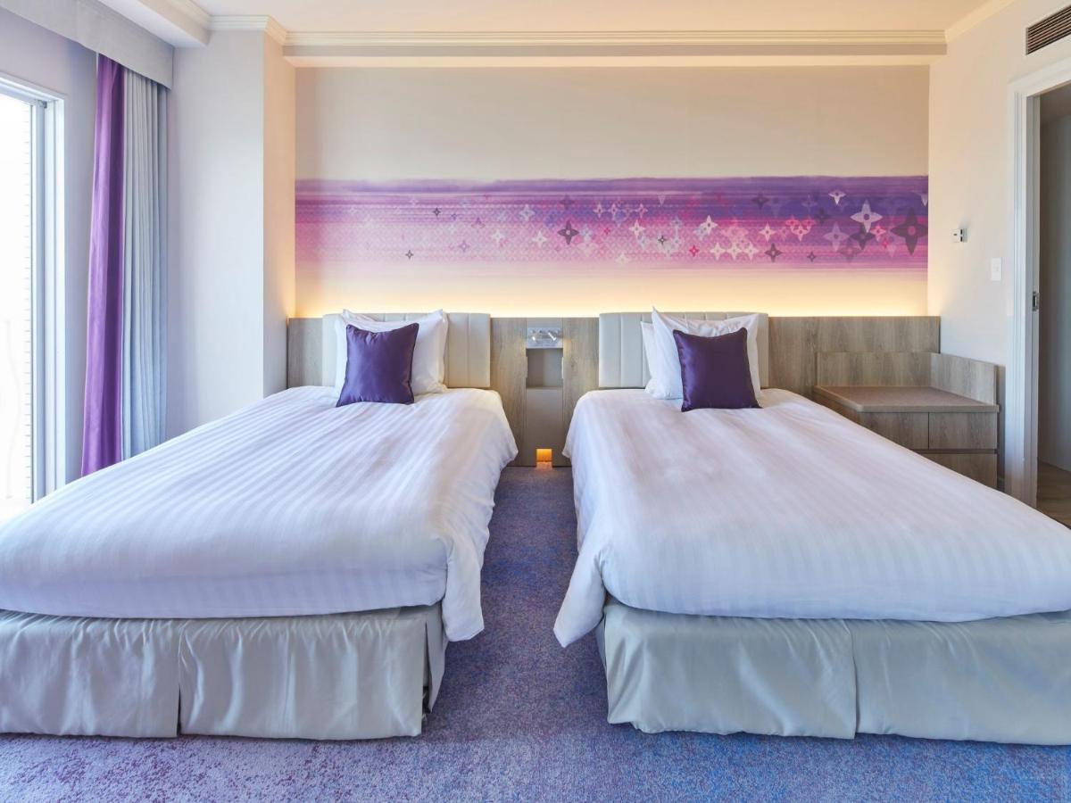 Grand Nikko Tokyo Bay Maihama Hotel Urajaszu Kültér fotó The photo shows a hotel room featuring two twin beds with white bedding and purple accent pillows. The beds are positioned next to each other, with a light-colored headboard. Behind the beds, there is a decorative wall with a gradient of purple hues.