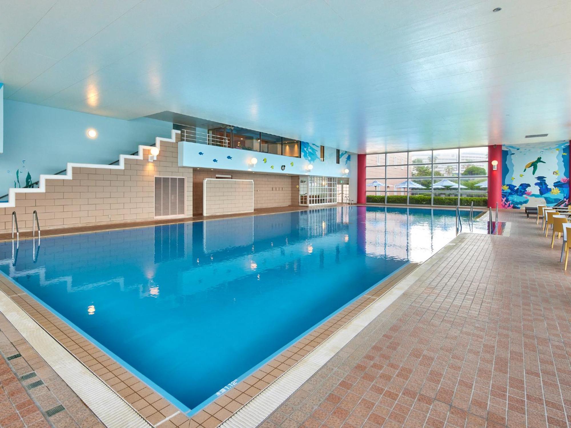 Grand Nikko Tokyo Bay Maihama Hotel Urajaszu Kültér fotó The photo shows an indoor swimming pool area with a spacious design. The pool has a clear blue water surface and is surrounded by a tiled deck. On one side of the pool, there are steps leading into the water, and there are large windows letting in na