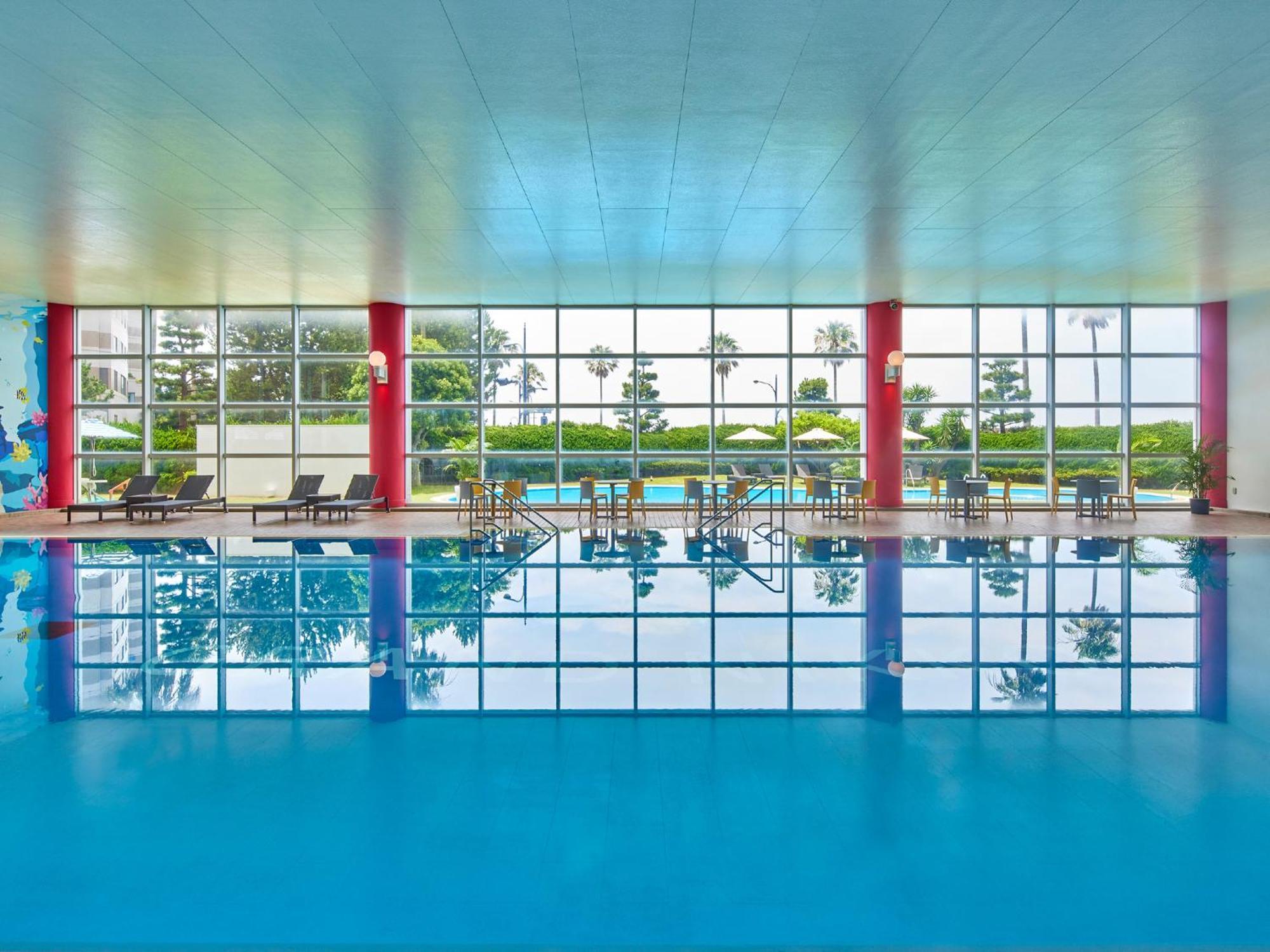 Grand Nikko Tokyo Bay Maihama Hotel Urajaszu Kültér fotó The photo shows an indoor swimming pool with bright blue water. The pool area is spacious, characterized by large windows that allow natural light to flood in, creating a vibrant atmosphere. The walls are painted in a soft color, with accents of red.