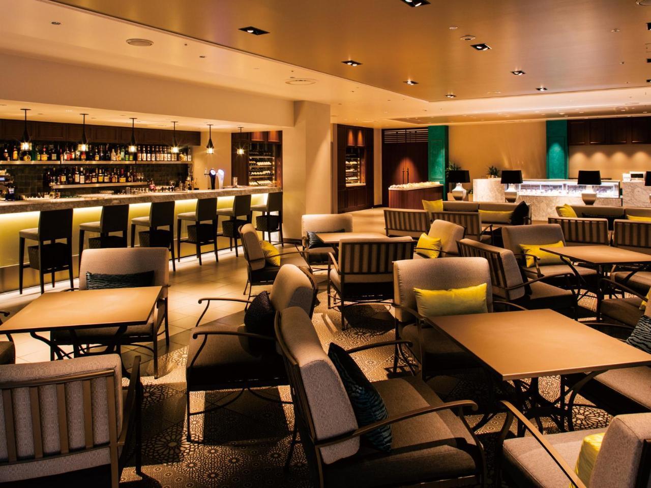 Grand Nikko Tokyo Bay Maihama Hotel Urajaszu Kültér fotó The photo shows a modern, upscale lounge or bar area. It features a variety of seating options, including cushioned chairs and tables arranged for conversation. The space is well-lit, with warm lighting that creates an inviting atmosphere. In the bac